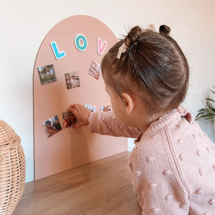 Ett barn tittar på familjens fotomagneter på en magnettavla