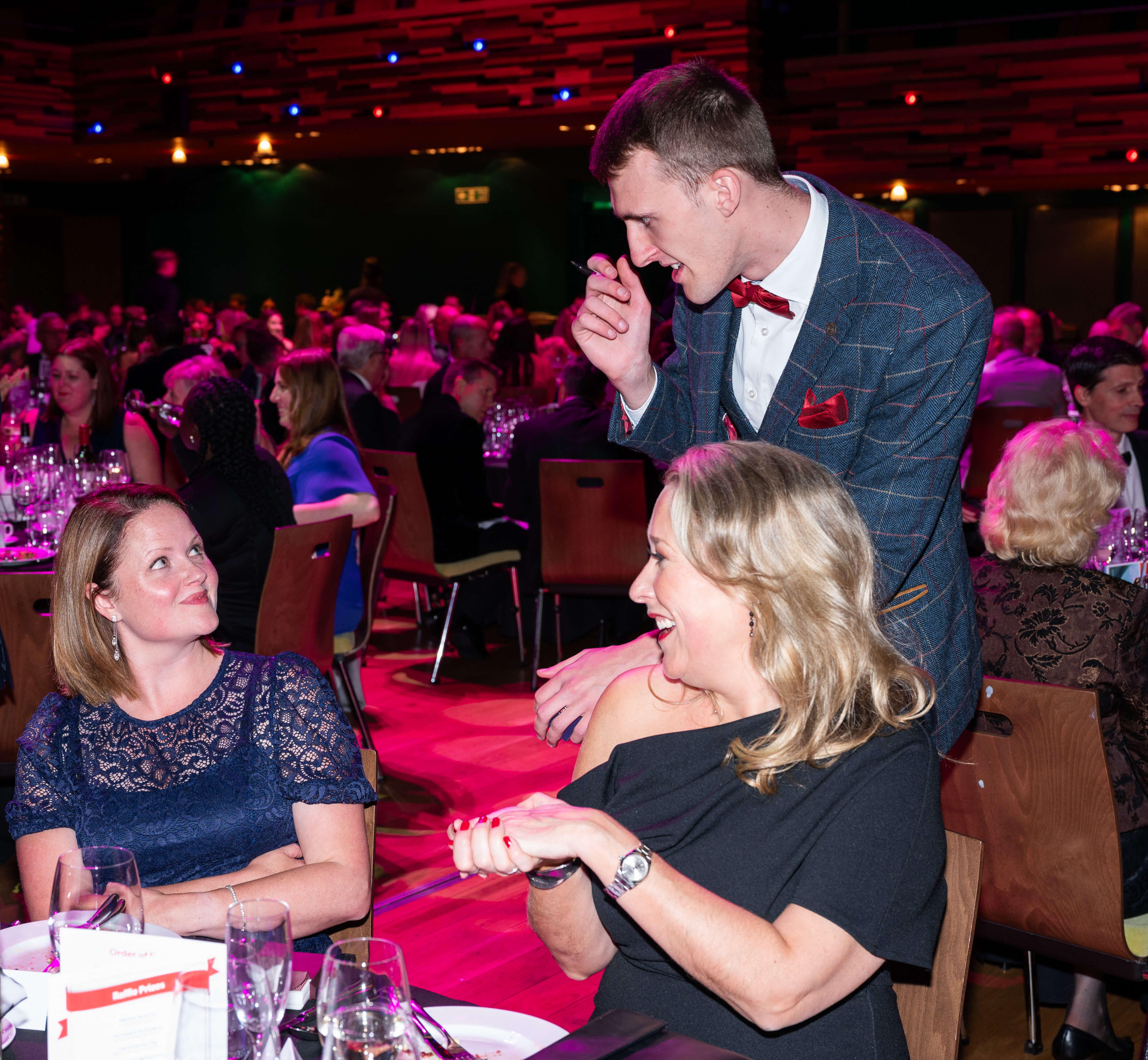 Professional event magician performing close-up magic for guests during a dinner