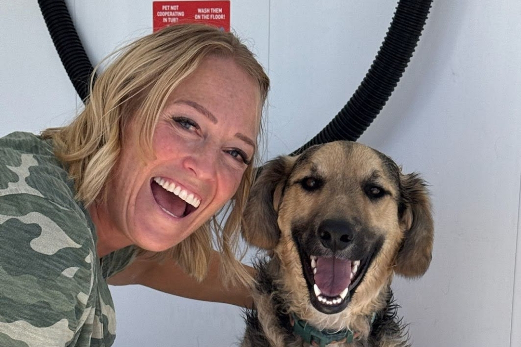 Happy woman washing her smiling dog at Jag’s Pet Wash self-service dog wash station