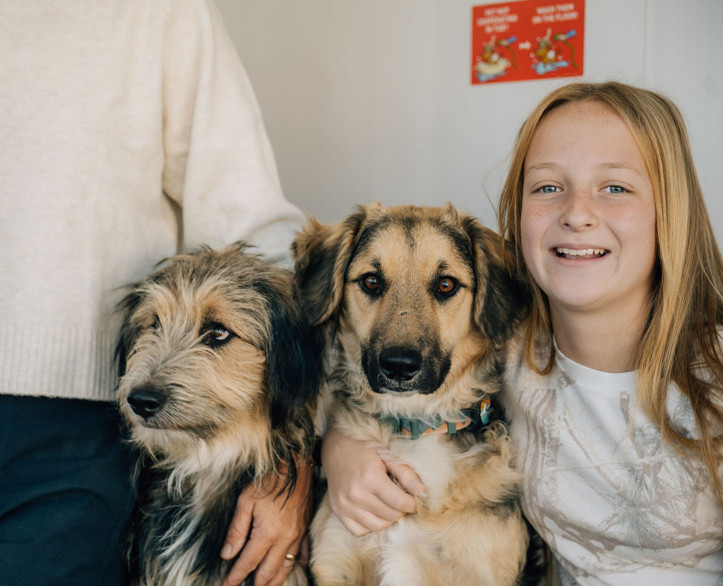 Smiling girl with two happy dogs after a bath at Jag’s Pet Wash in Pocatello