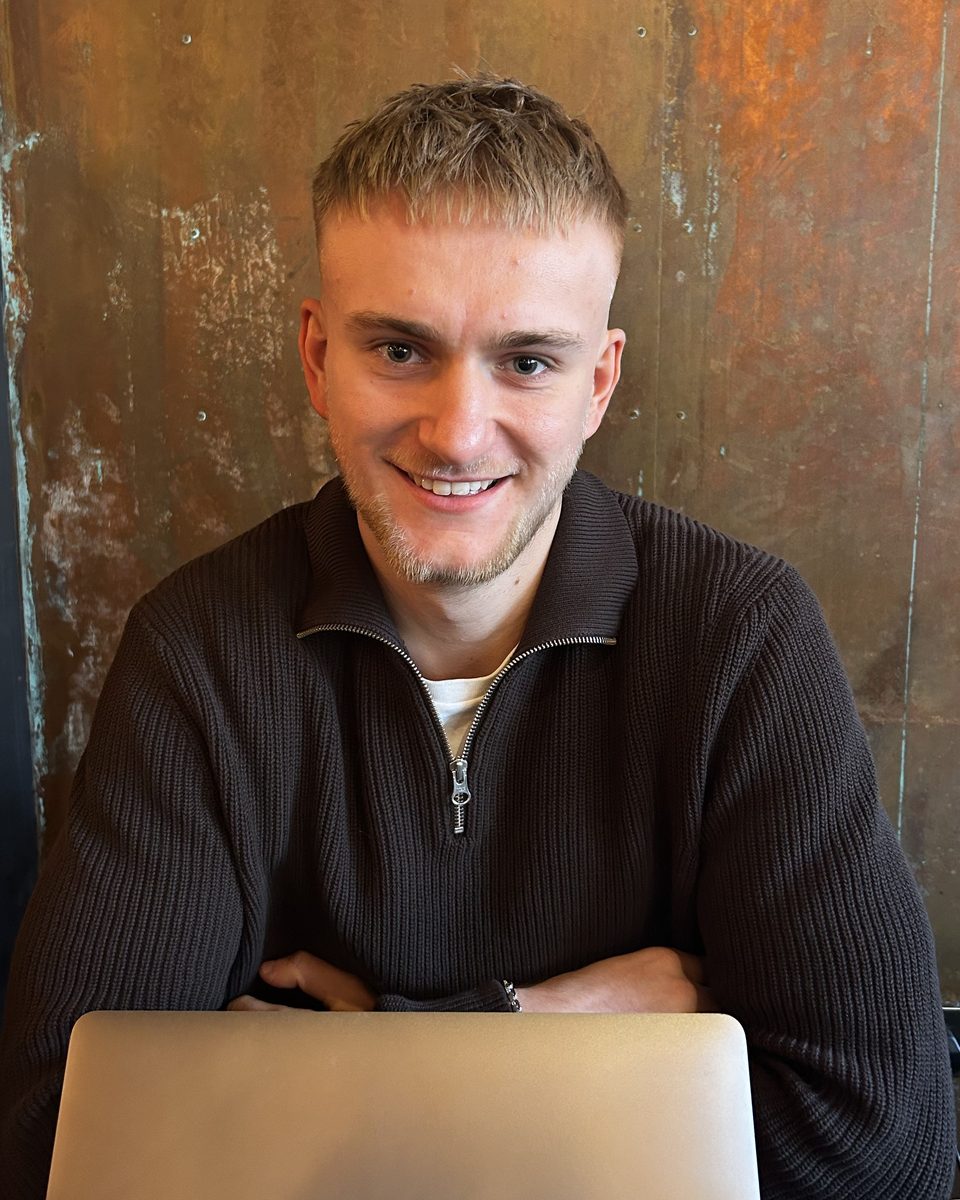 Oli Hudson, founder of TradeLink, smiling and sitting at a table