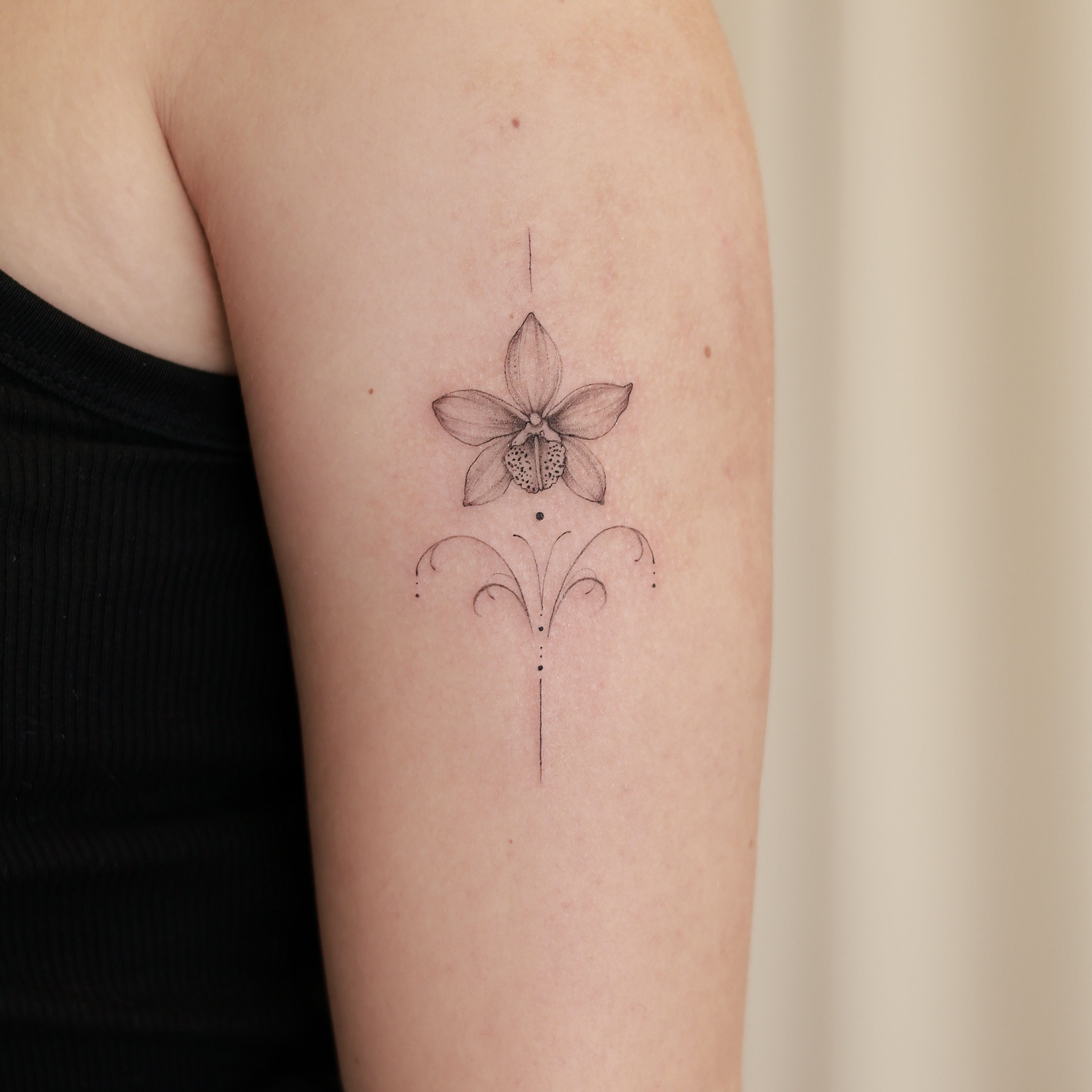 Tatouage fine line d'une fleur ornementale sur le bras