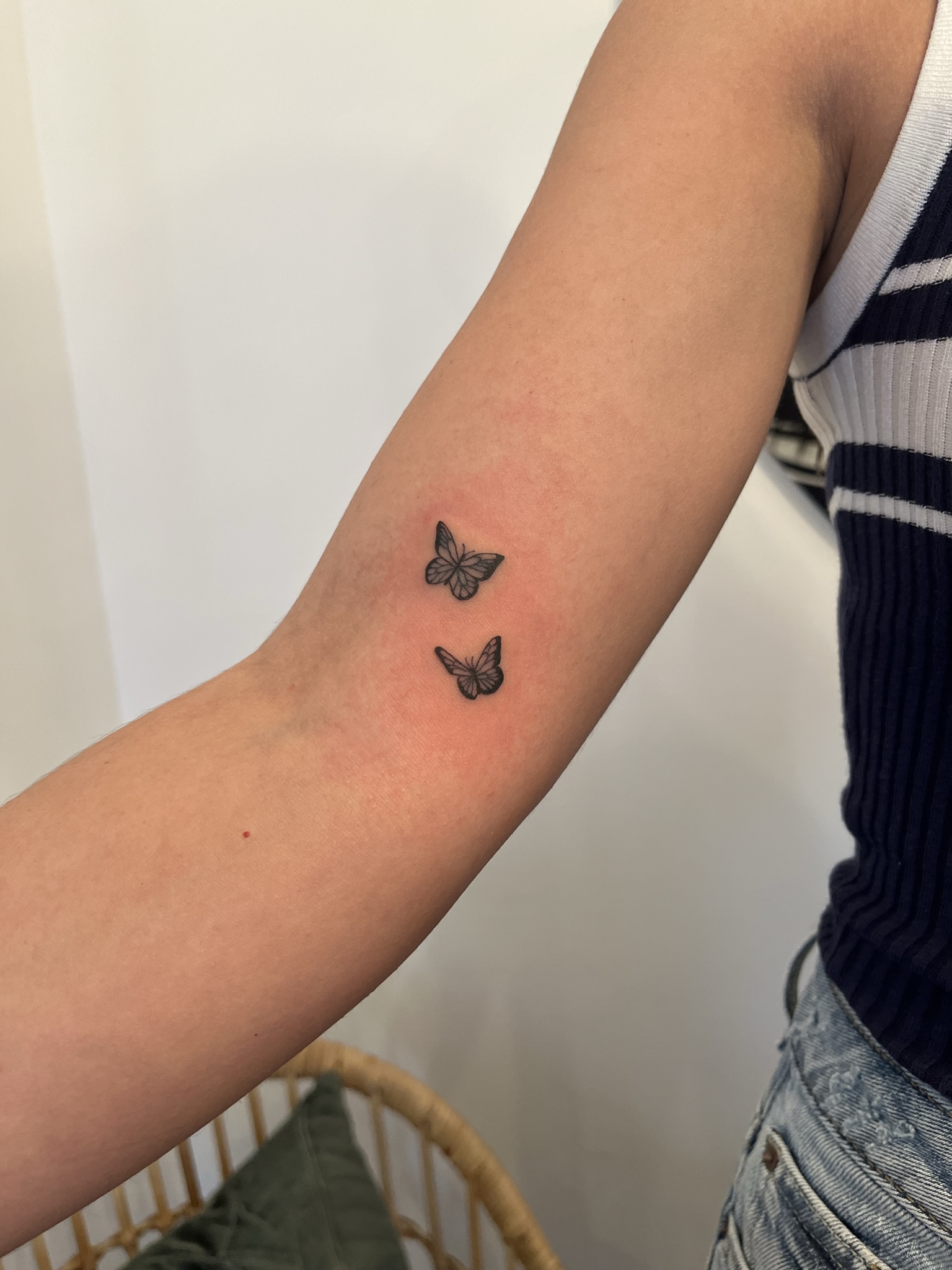 Tatouage fine line de deux petits papillons sur l’avant-bras
