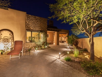 Outdoor landscape lighting along a stone pathway in a southwestern-style home, with pathway lights accentuating the architecture and surrounding desert plants.