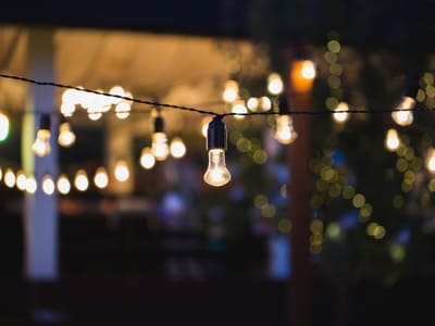 String lights hanging across a backyard patio area, creating a warm and inviting ambiance for outdoor gatherings.