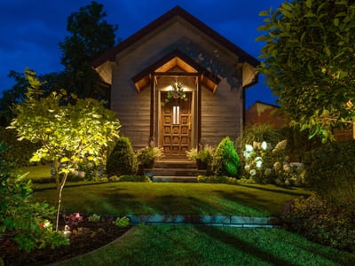 Landscape lighting highlighting the entrance of a home, with lights accentuating the front door, garden, and well-maintained lawn.