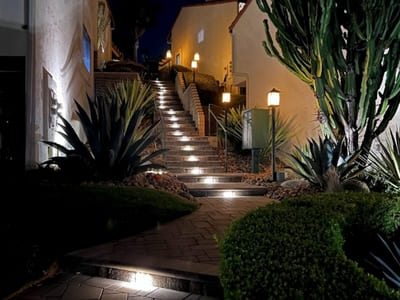 Illuminated outdoor staircase with built-in step lights, surrounded by lush desert landscaping, enhancing safety and aesthetics in a residential setting.