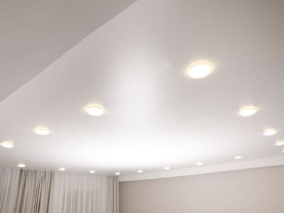 Recessed ceiling lights evenly illuminating a contemporary room, providing bright and uniform lighting.