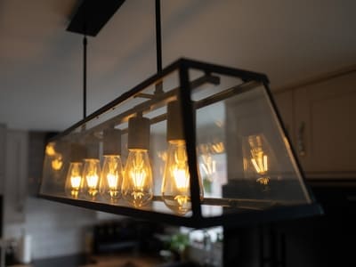 Pendant light fixture with multiple exposed bulbs, adding a warm and stylish glow to a modern kitchen space.