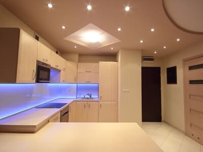 Modern kitchen in Carlsbad with recessed ceiling lights and under-cabinet LED lighting, providing a warm and well-lit cooking space.