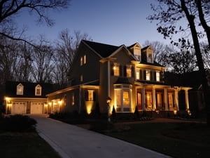 Elegant home with uplighting along the exterior walls, highlighting the architecture and creating a welcoming nighttime scene.