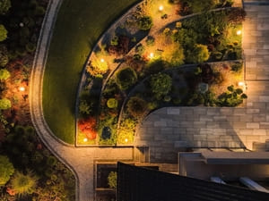 Aerial view of a garden at night, showcasing the well-planned landscape lighting that enhances the beauty of the garden paths and plants.