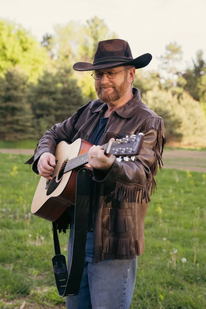 Terry Derosier outdoors playing his acoustic guitar
