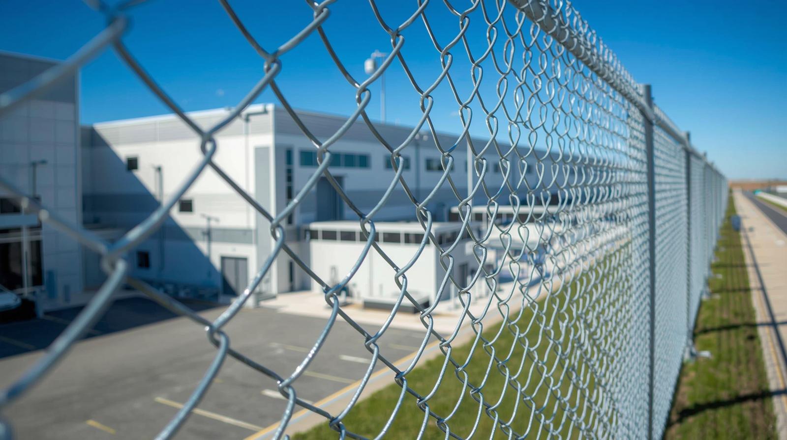 Commercial chain link fence installed around warehouse property providing perimeter security. Commercial chain link fence installed around warehouse property providing perimeter security.