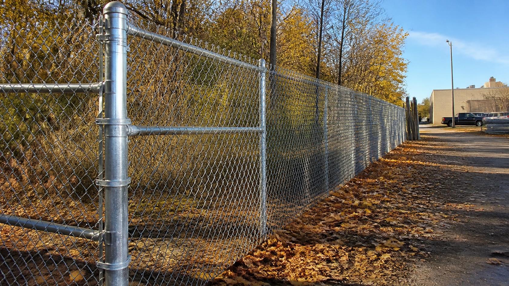 Chain link fence at a business property in Belvidere, IL being inspected for damaged mesh, loose posts, gates, and other repair needs before winter.