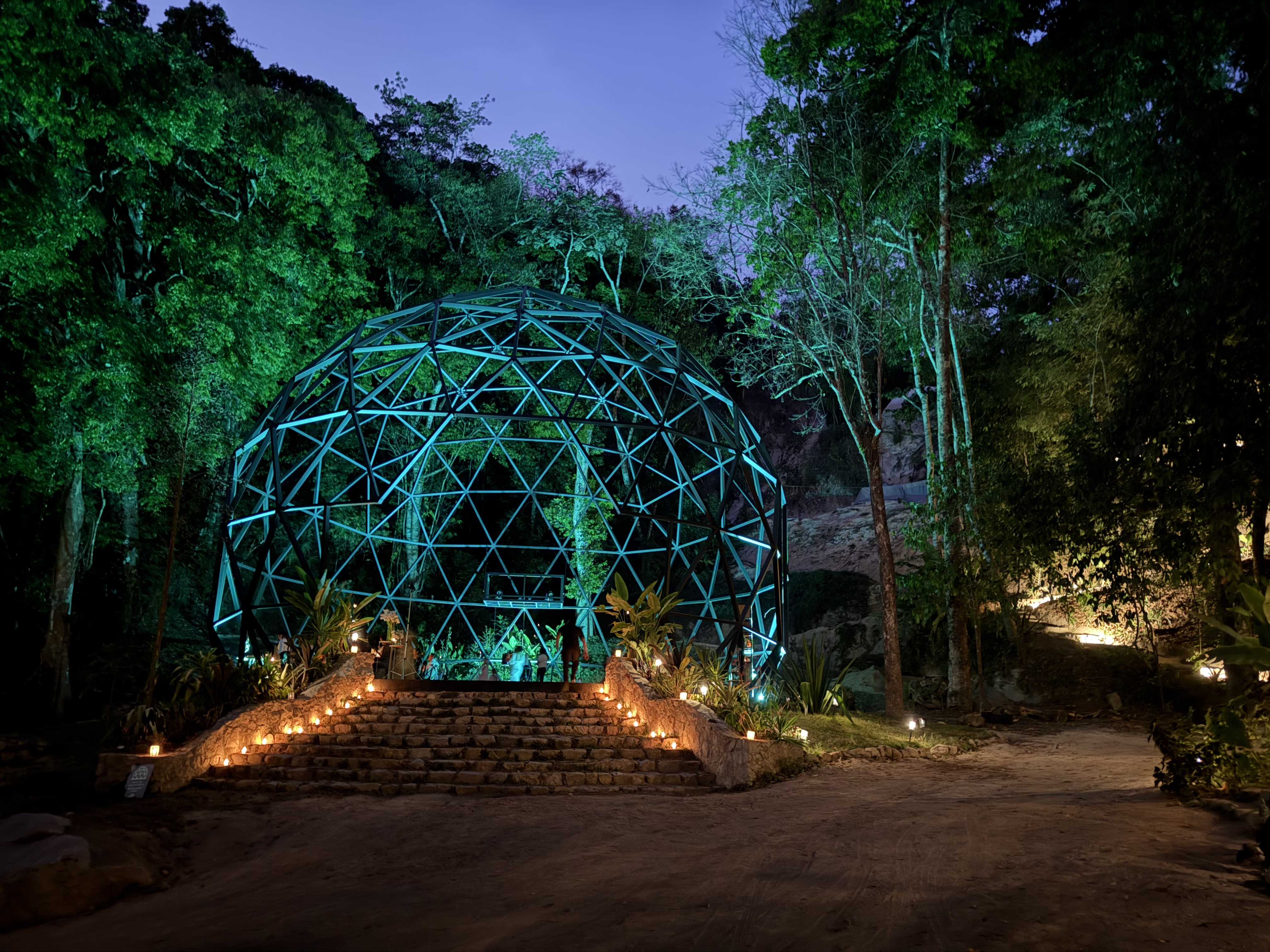 Illuminated geodesic dome structure in the forest at night