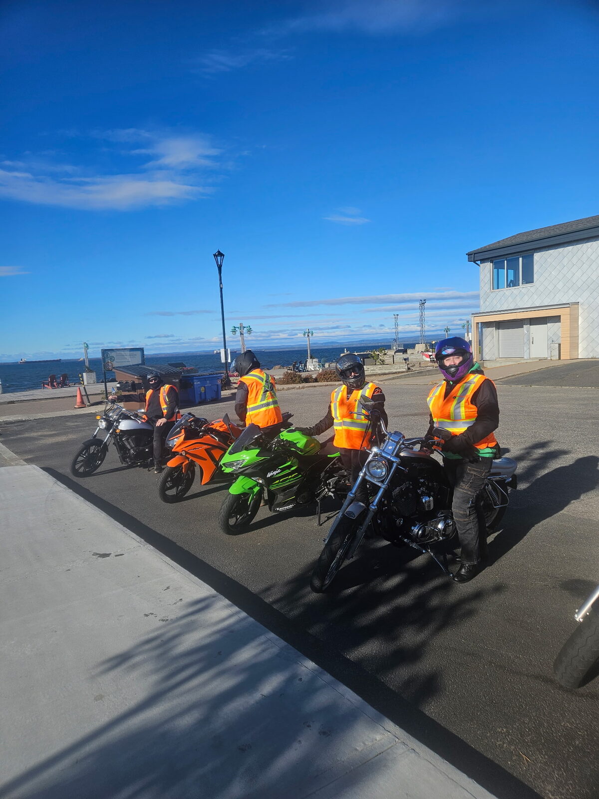 Élèves en dossard sur leurs motos devant la mer, par un ciel bleu