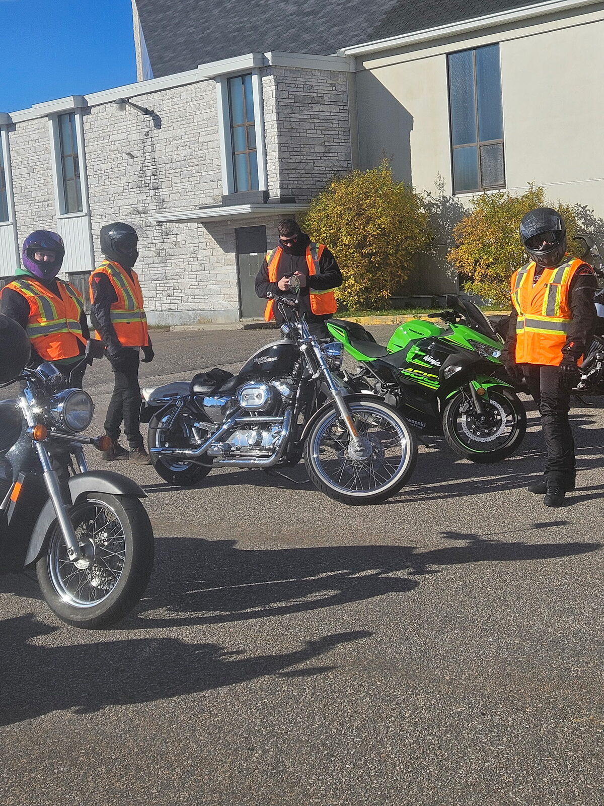 Un groupe d'élèves en dossard orange, chacun sur une moto de l'école