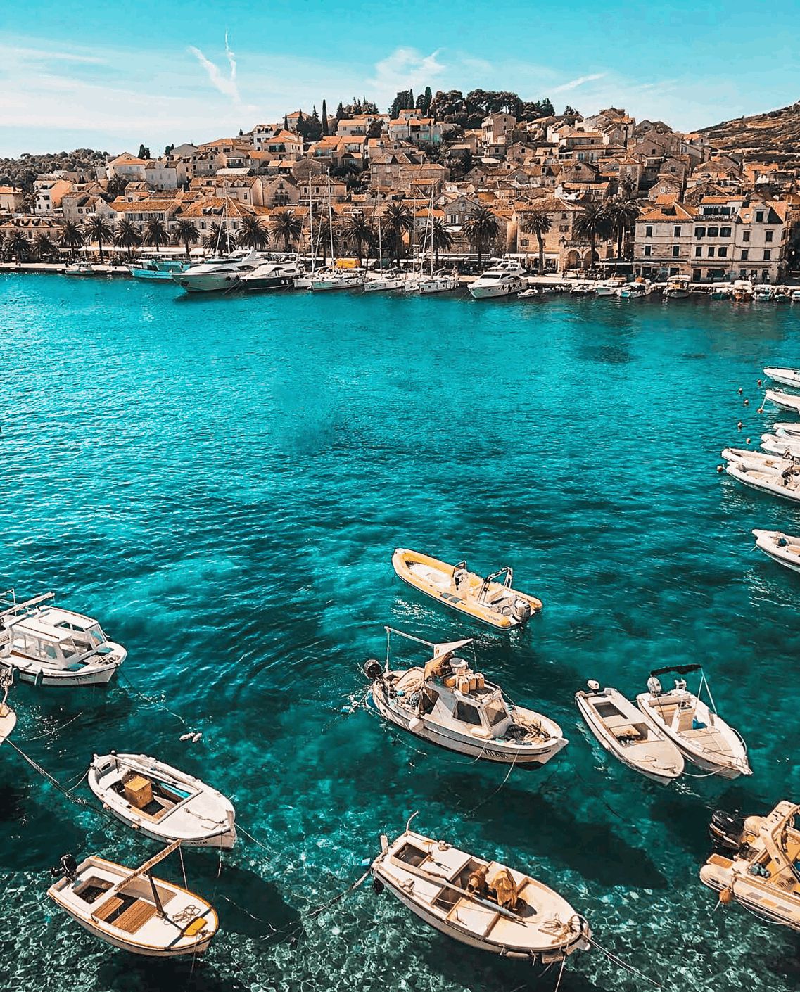 Boats floating in turquoise water beside a coastal town Boats floating in turquoise water beside a coastal town