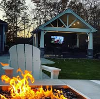 Fire pit and pavilion with landscape lighting at dusk by American Landscape Construction