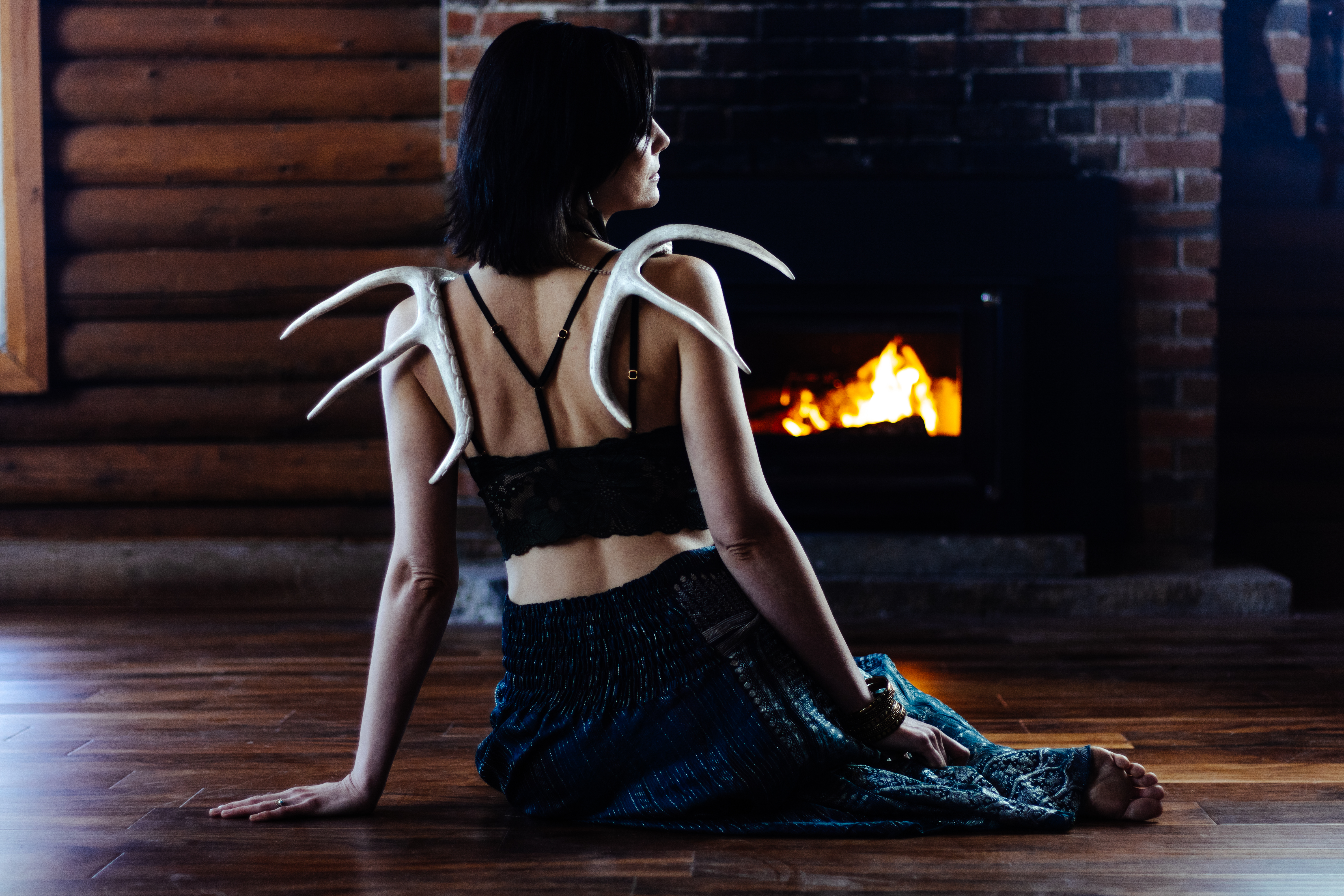 Samia by the cabin fireplace, antlers worn like wings