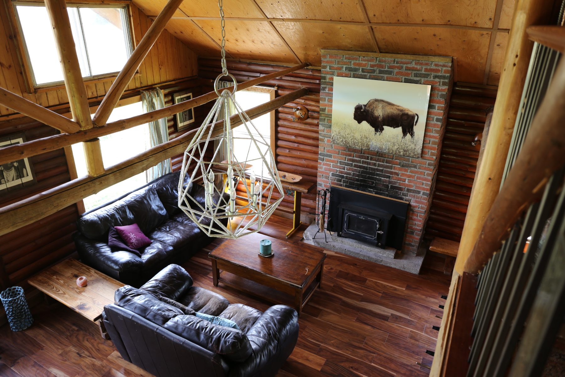 Living room with brick fireplace and vaulted wood ceiling, seen from the loft