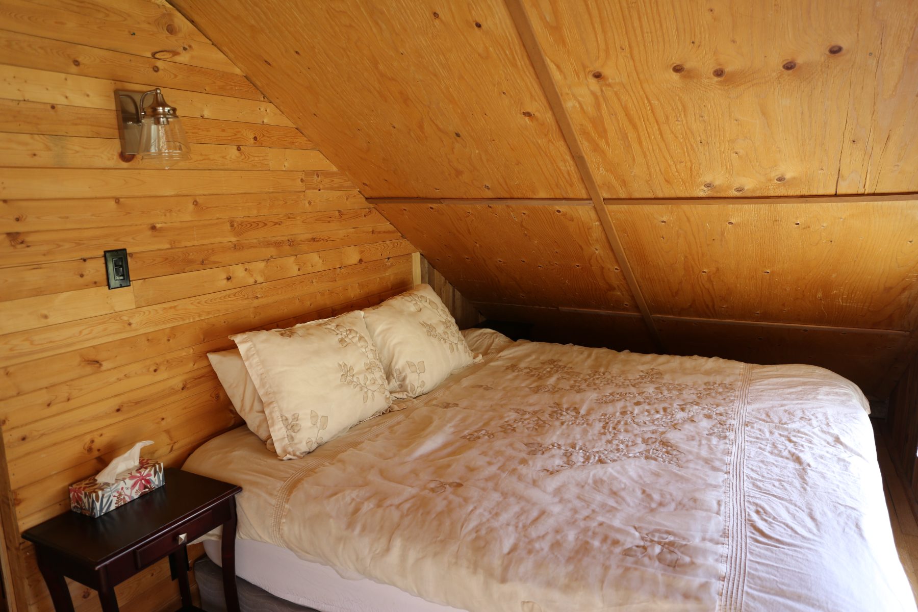 The main bedroom bed tucked under the sloping wood eaves