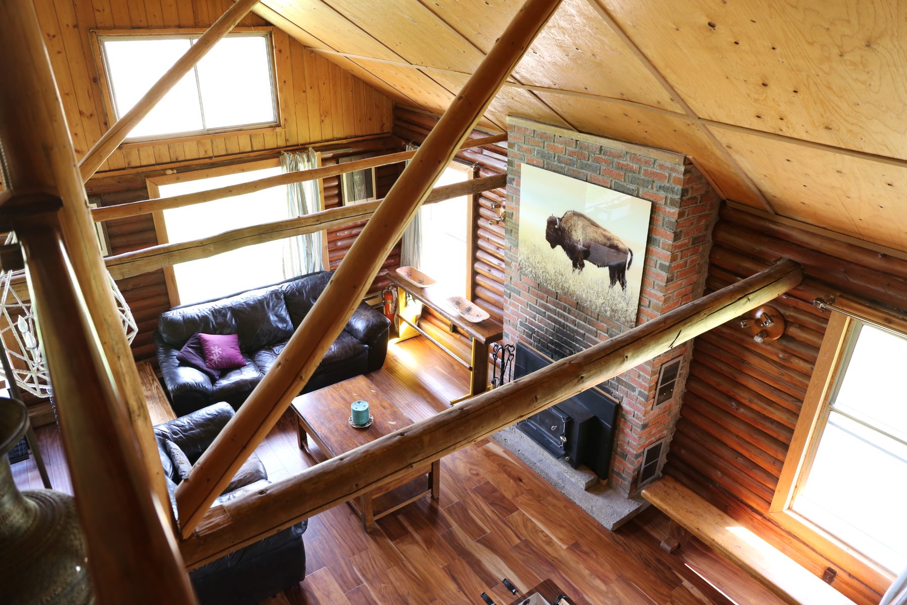 Looking down from the loft onto the sofas, coffee table and brick woodstove