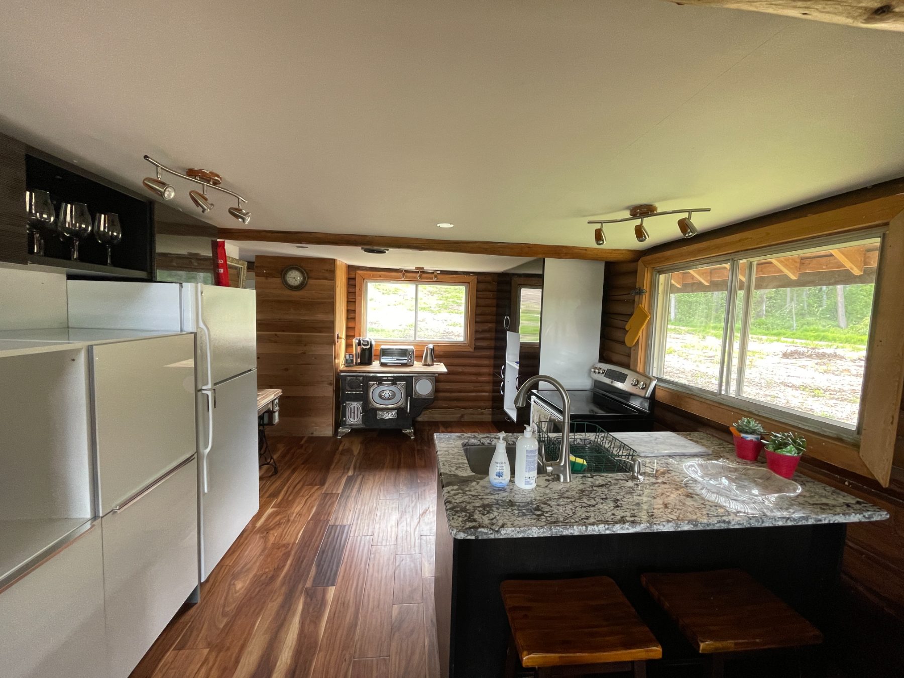 The kitchen—granite island with sink and stools, electric range, and the antique cookstove beyond