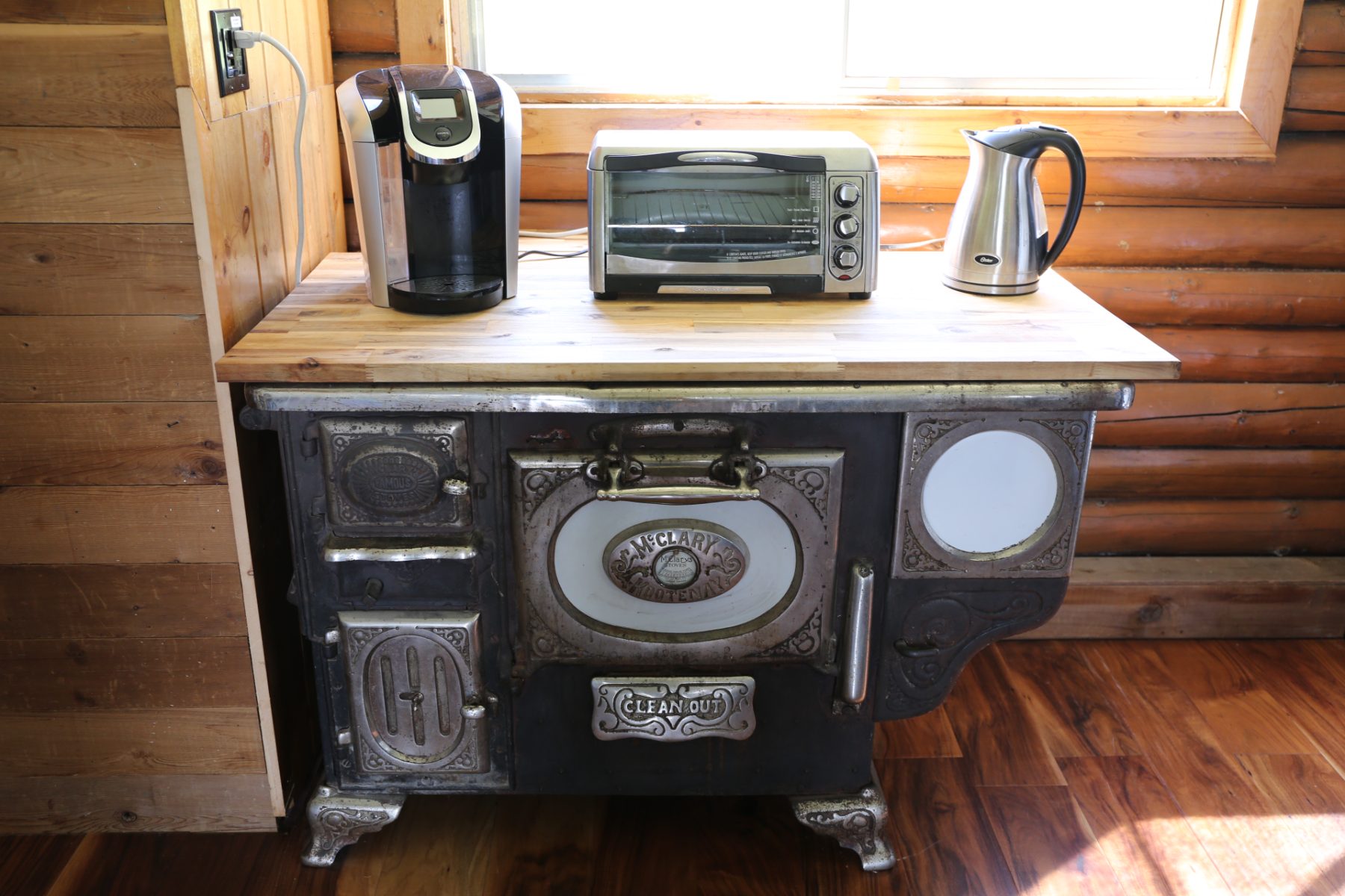 The antique McClary cookstove with coffee maker, toaster oven and kettle on its butcher-block top