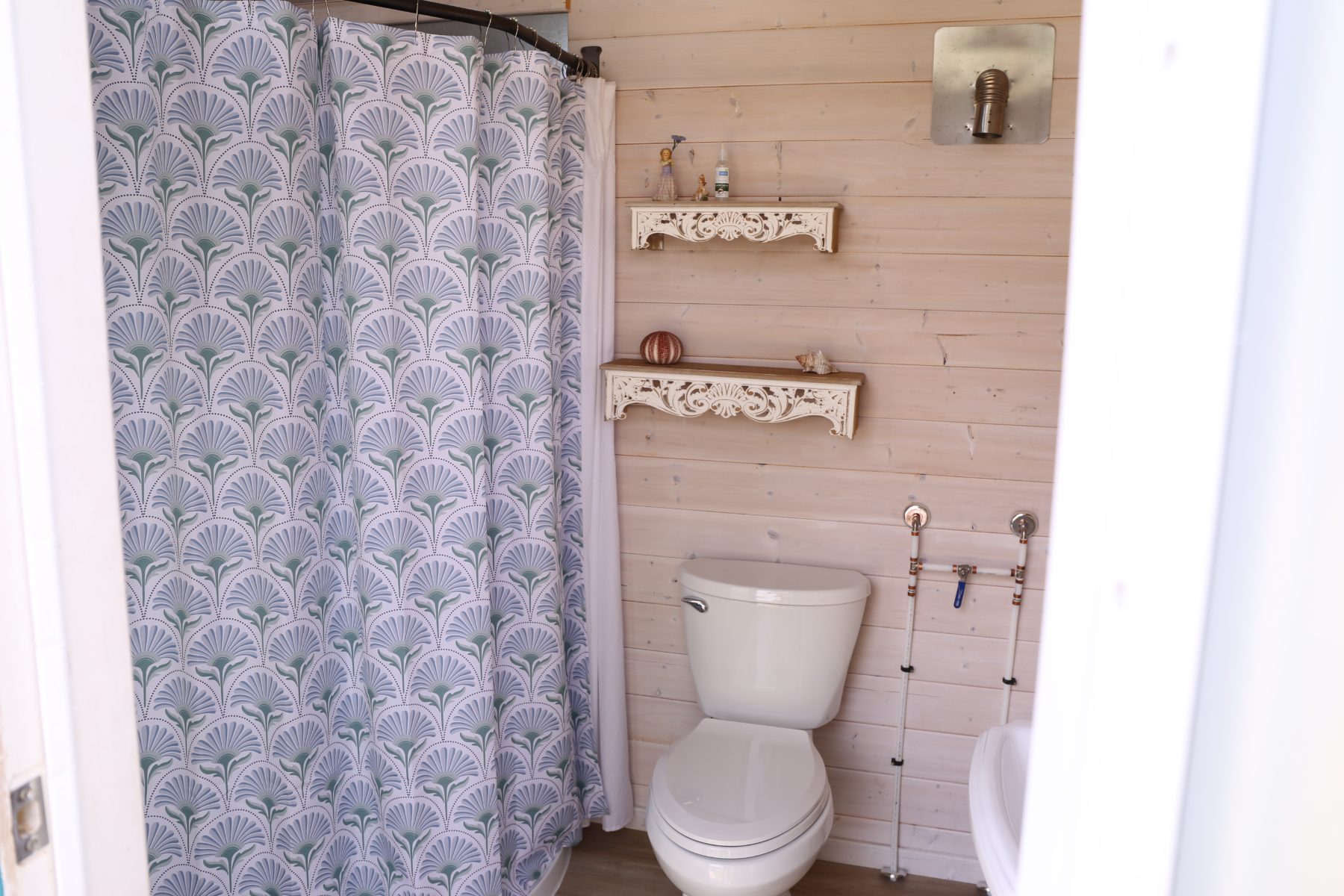 The washhouse shower with its patterned curtain and carved white shelves