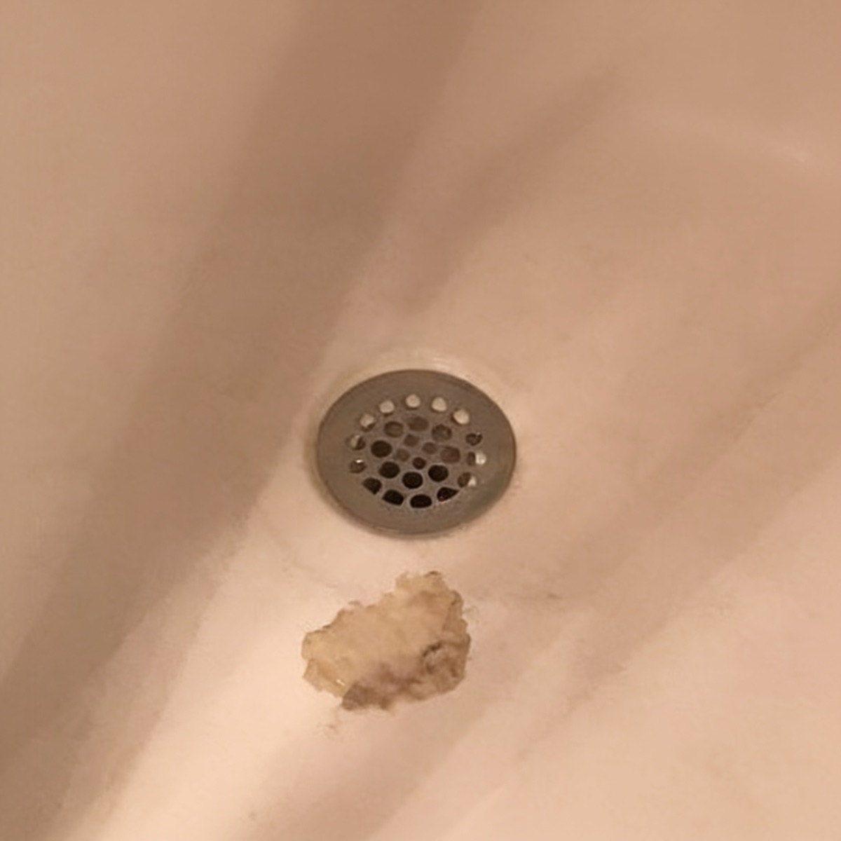 Tub drain before refinishing: yellowed finish with built-up residue