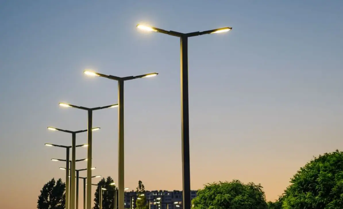 Rows of lit double-arm street light poles at dusk