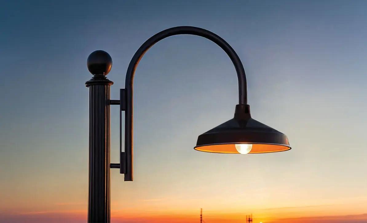 Gooseneck pole light with a lit shade at dusk