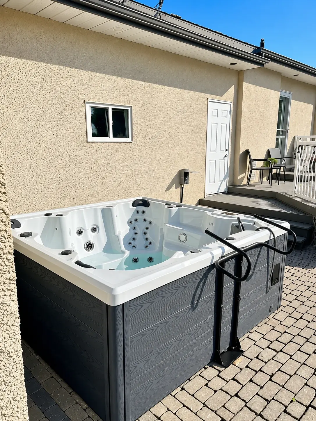 Finished white hot tub installed beside a stucco home