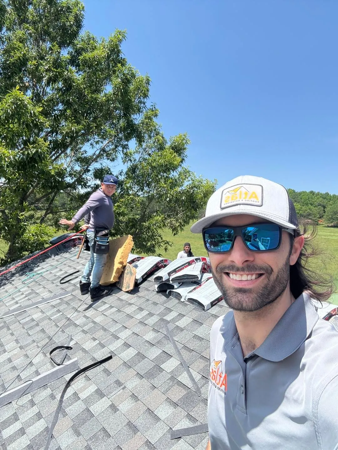 Smiling roofer with a coworker installing underlayment on a roof