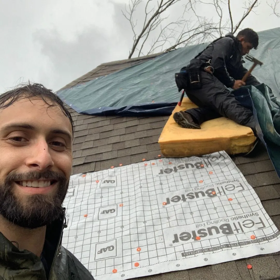Smiling roofer in a cap and sunglasses taking a selfie on a roof