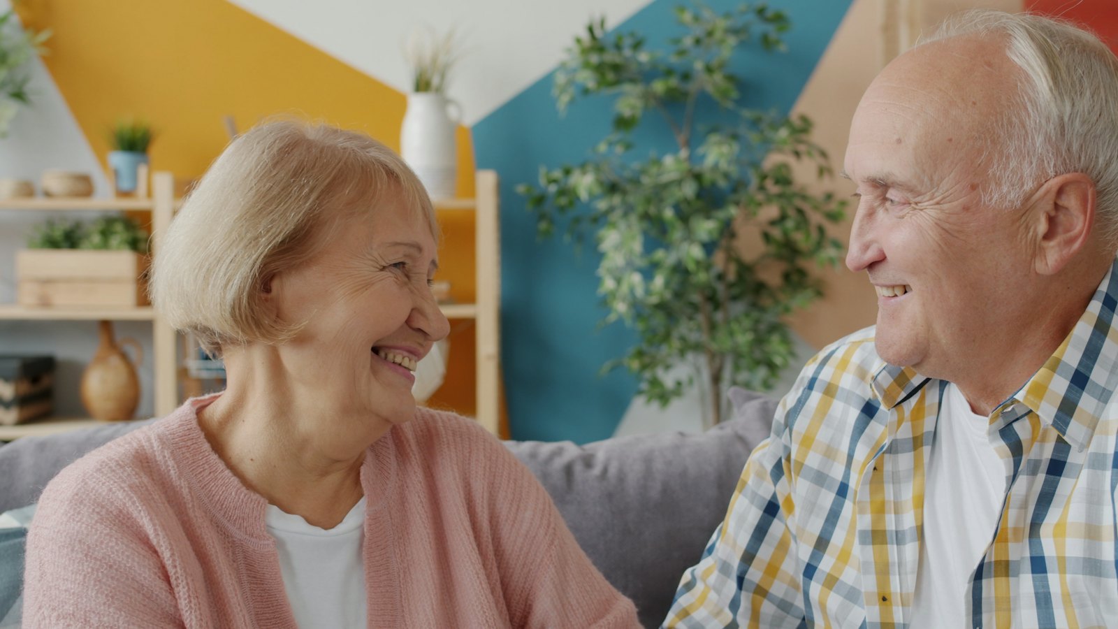 Older couple smiling at each other on a couch
