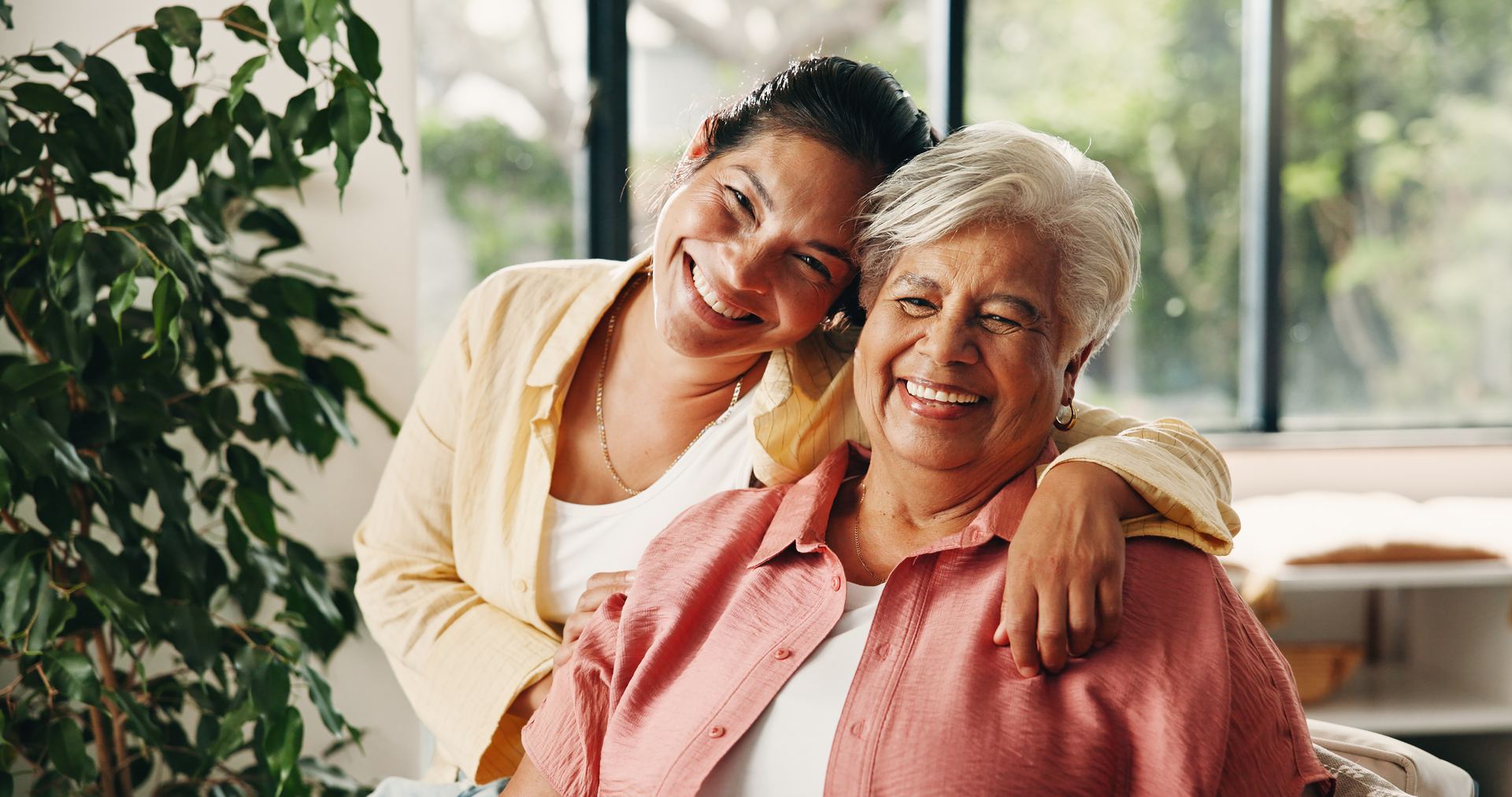 Mother and adult daughter hugging and smiling at home
