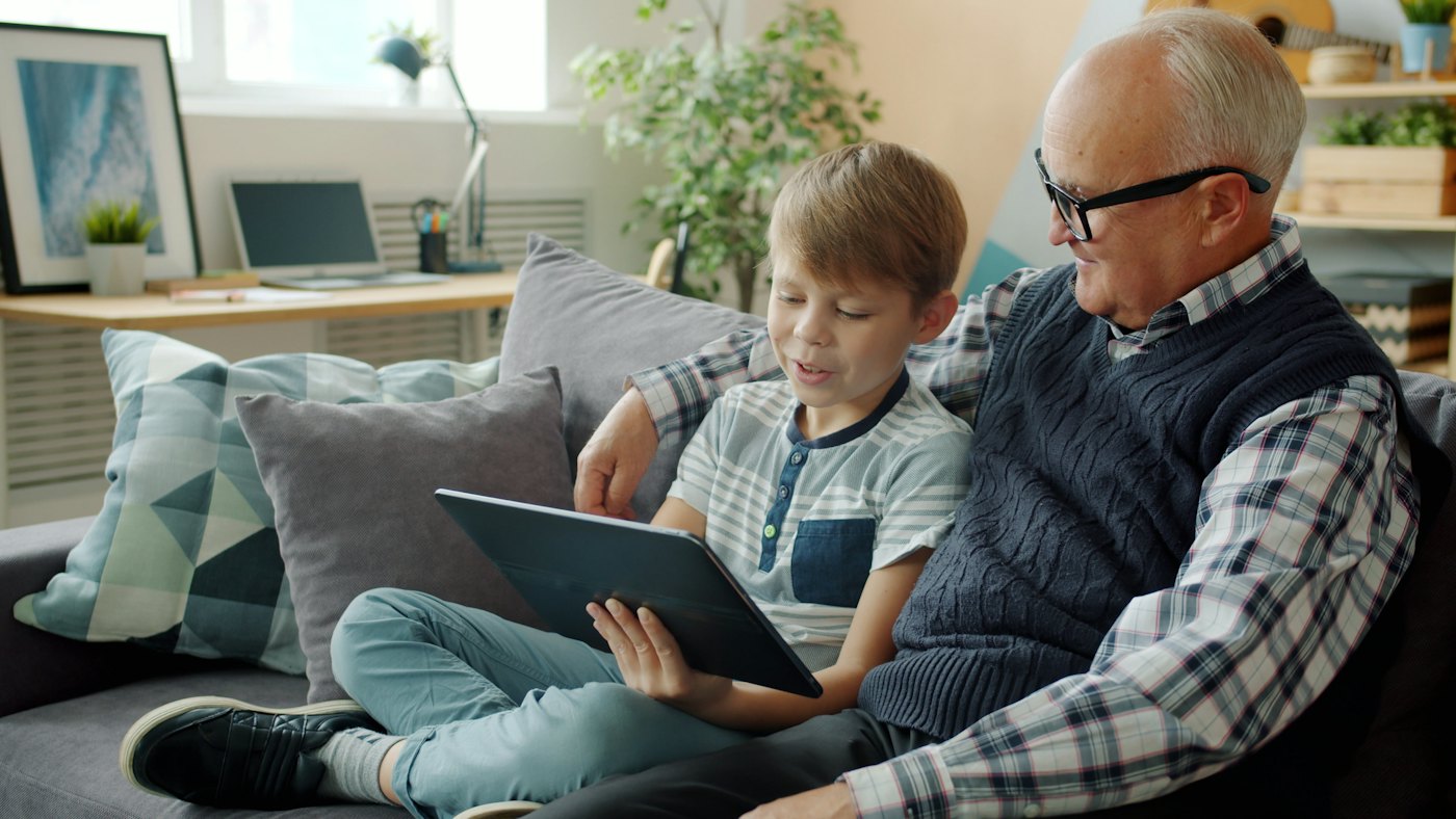 Grandfather and grandson looking at a tablet together on the couch