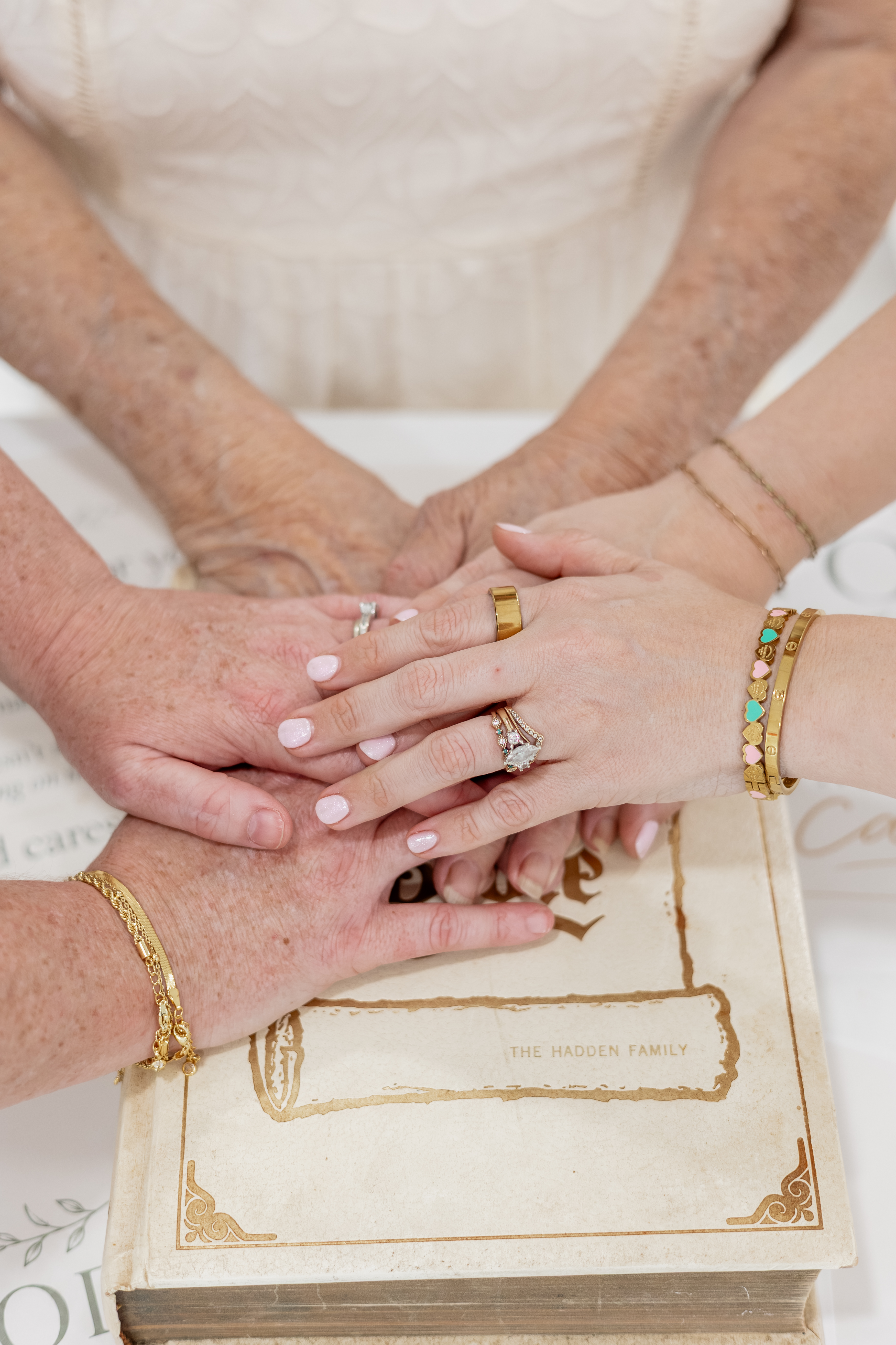 Three generations placing their hands together over The Hadden family Bible