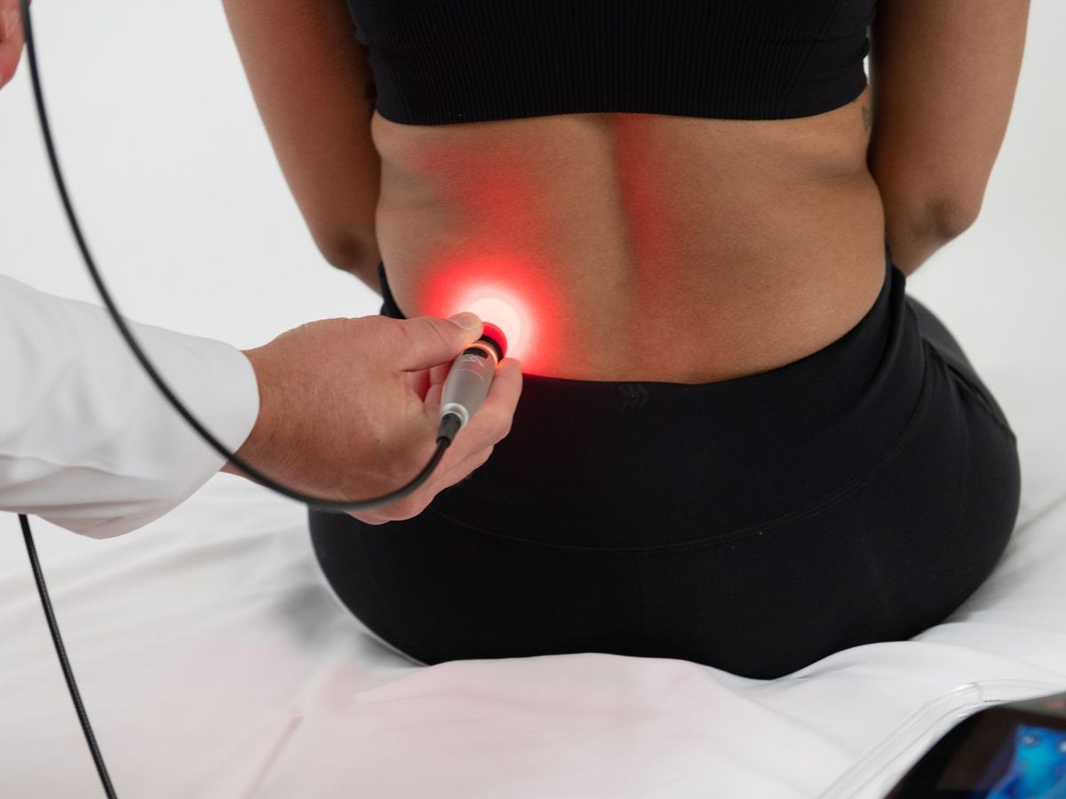Class IV laser therapy being applied to the low back with a handheld applicator