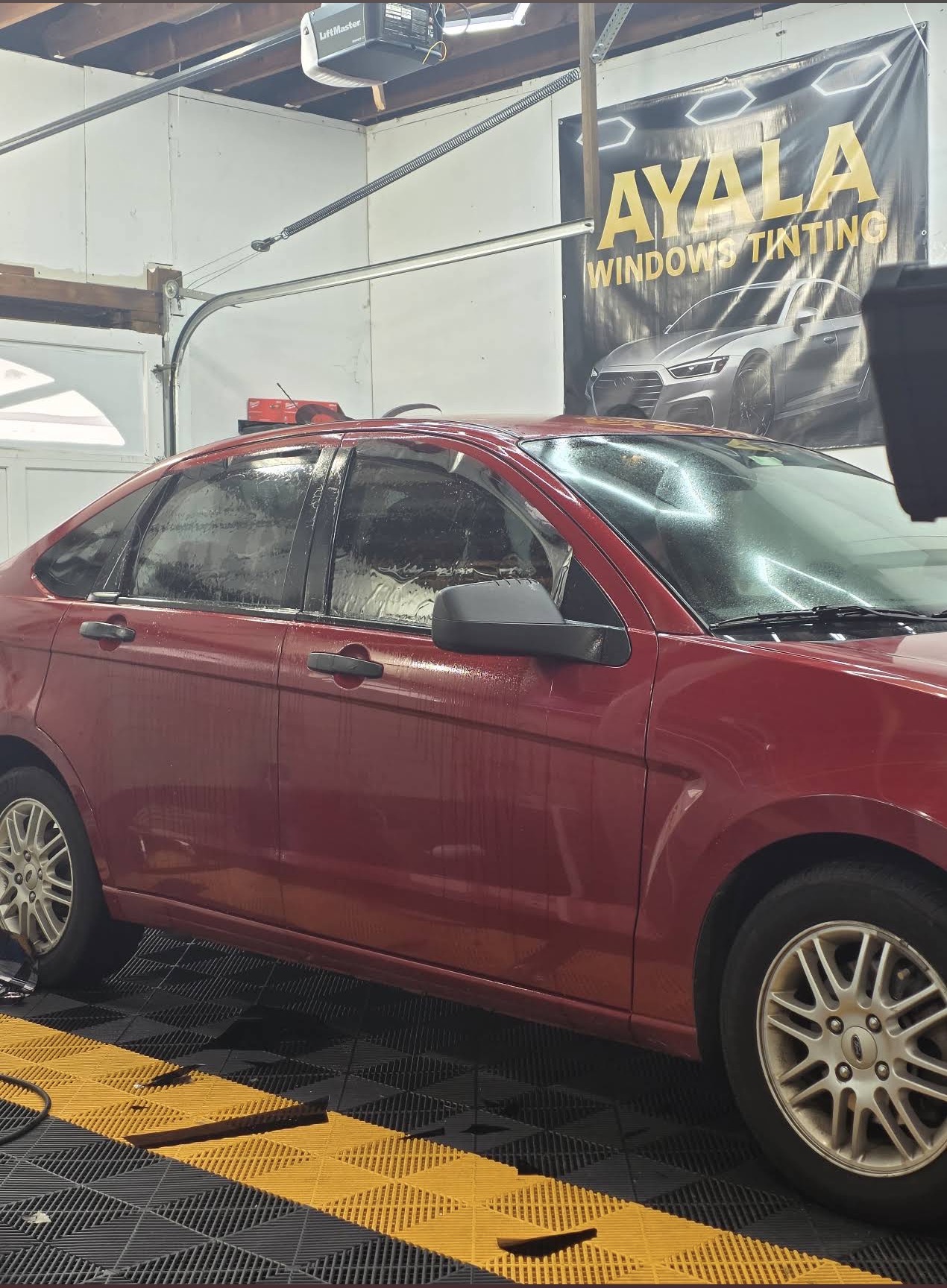 Red sedan inside the Ayala tint shop