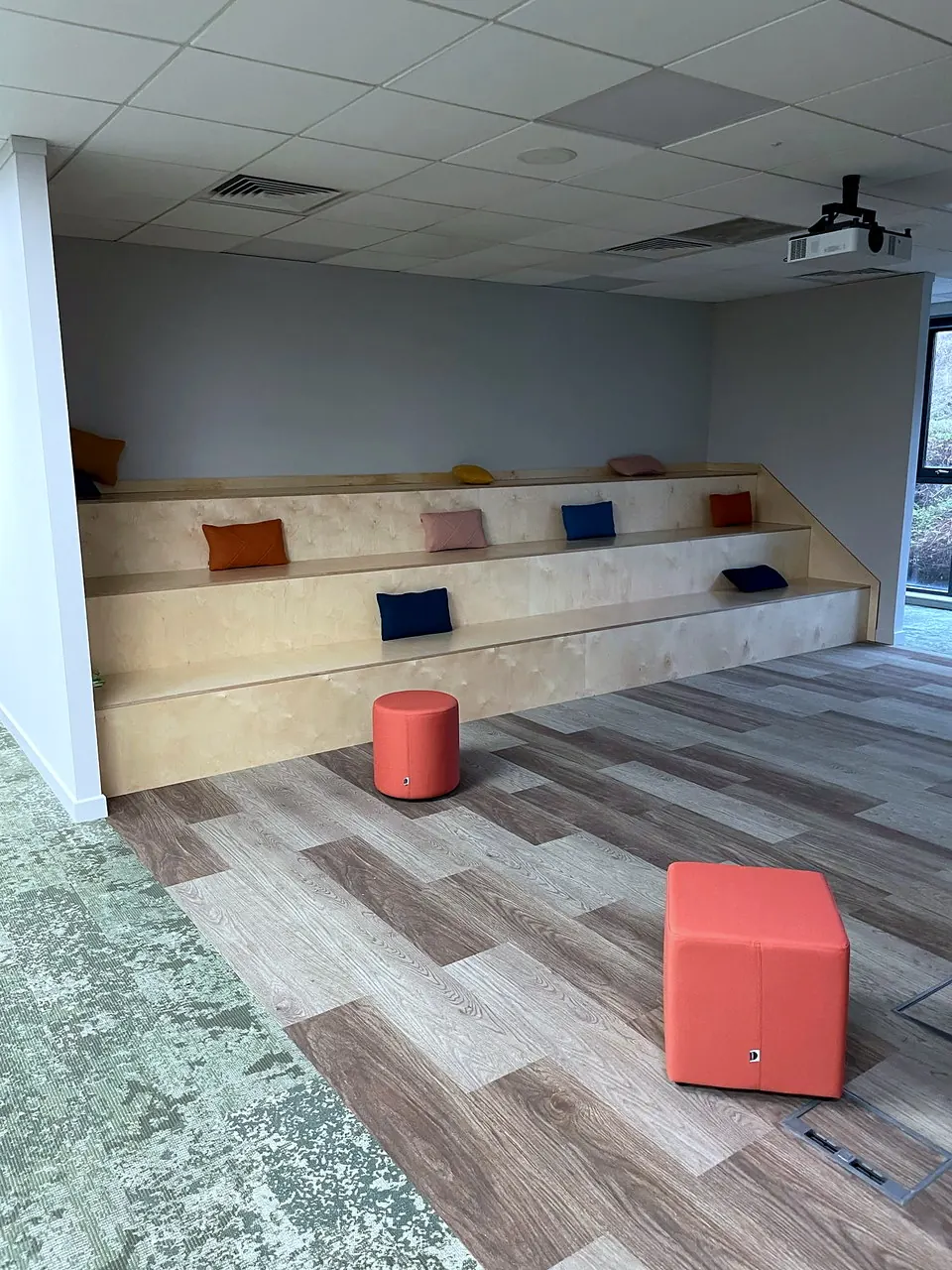 Tiered plywood bench seating with cushions in the presentation space at Bella & Duke.