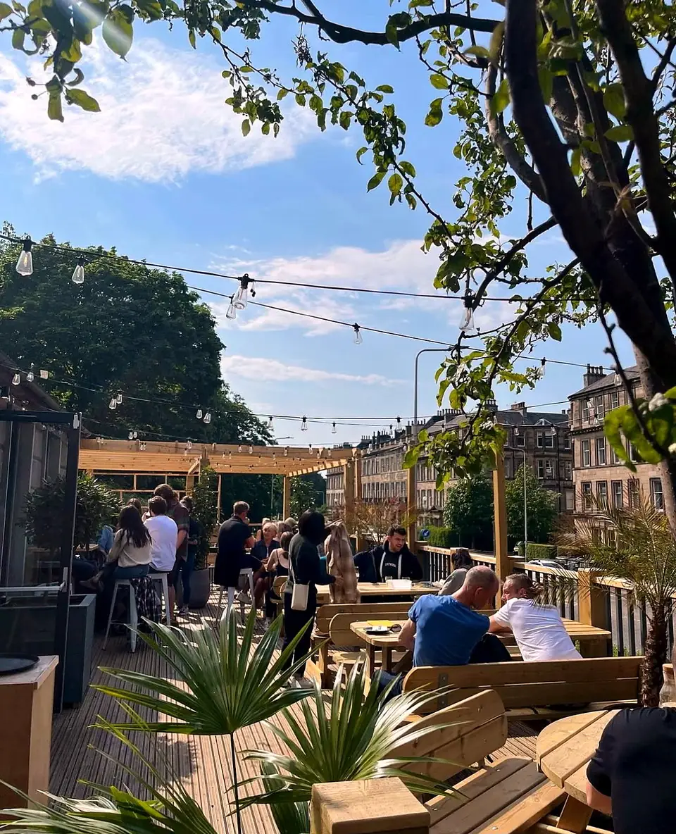 The raised outdoor terrace at Herringbone Abbeyhill under festoon lighting.