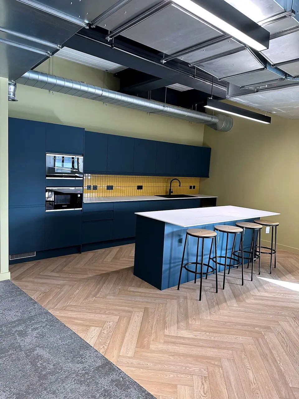 The tea point at 33 Castle Street, with navy cabinetry, a breakfast bar and herringbone flooring.