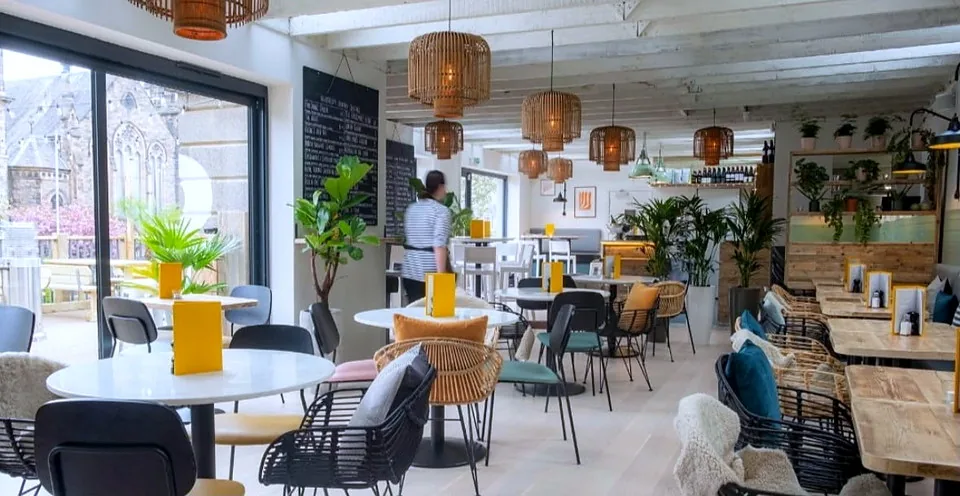 Tables, rattan pendants and the open dining room at Herringbone Abbeyhill.