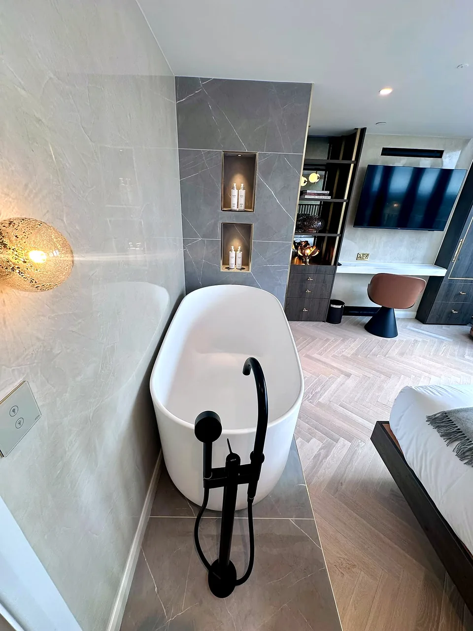 A freestanding bath against full-height stone at RIGH Residences.