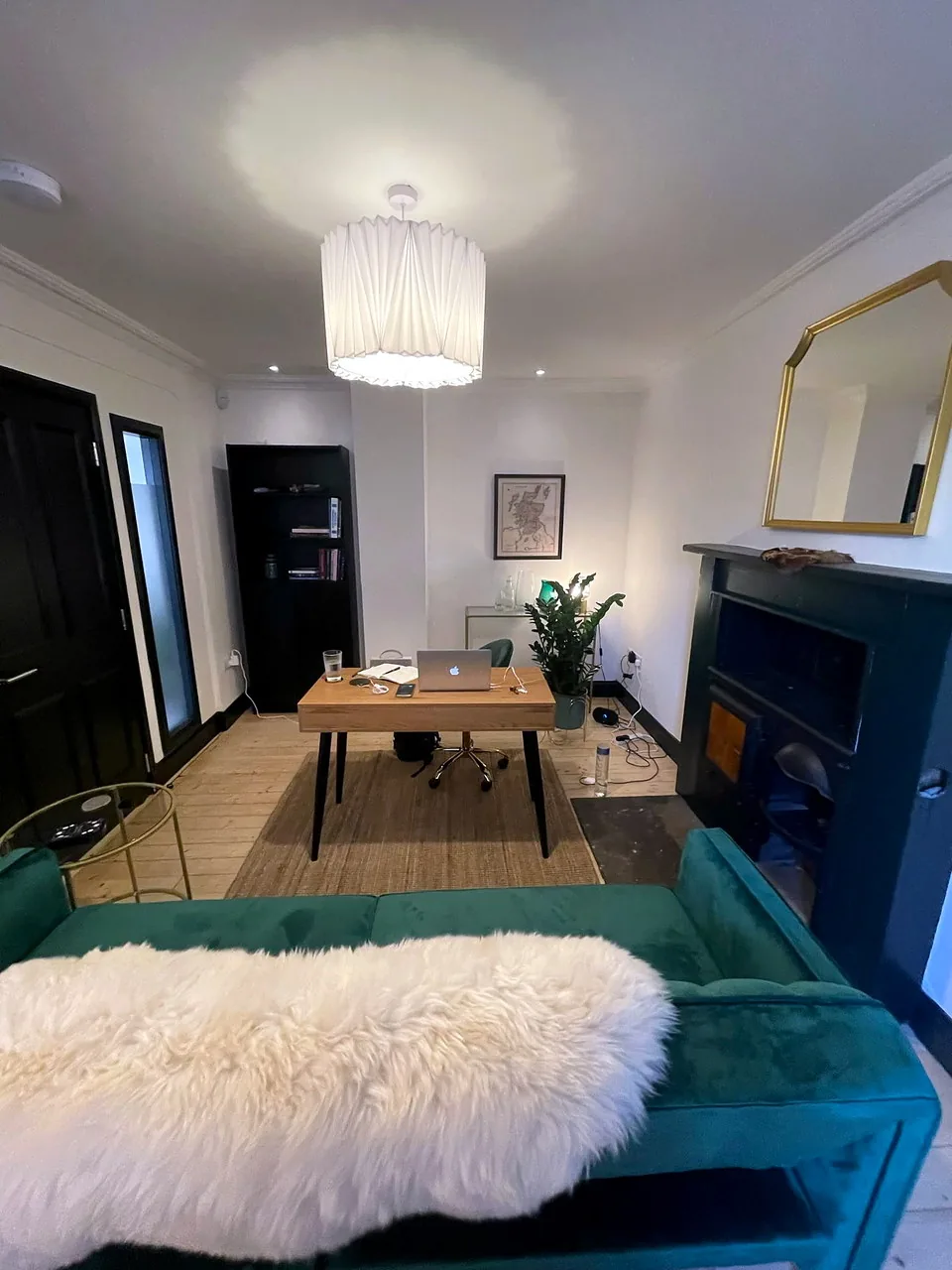 A consulting room at Solstice Wellness with a timber desk and green seating.