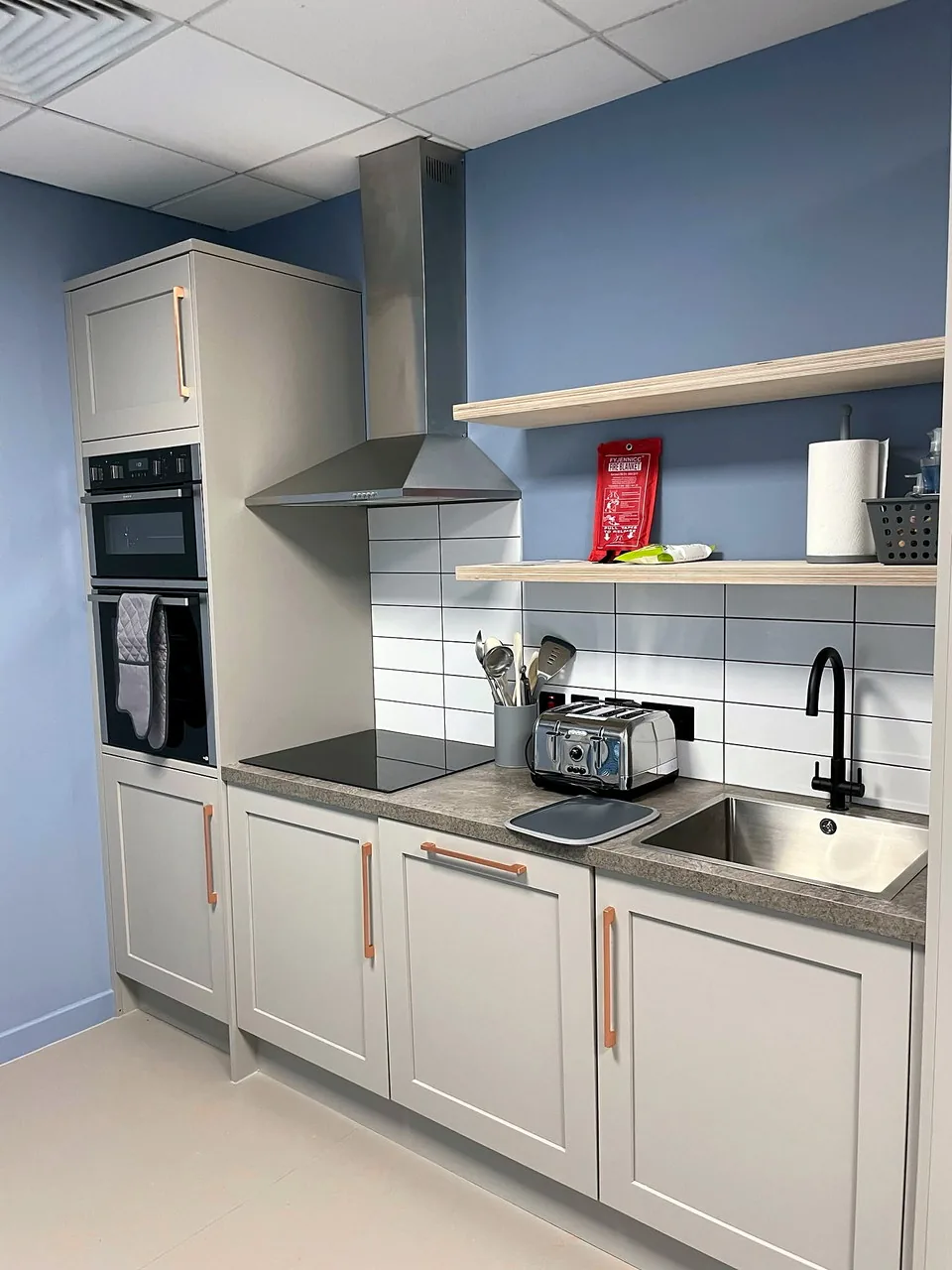The staff kitchen at Bella & Duke, with grey cabinetry and an extractor over the hob.